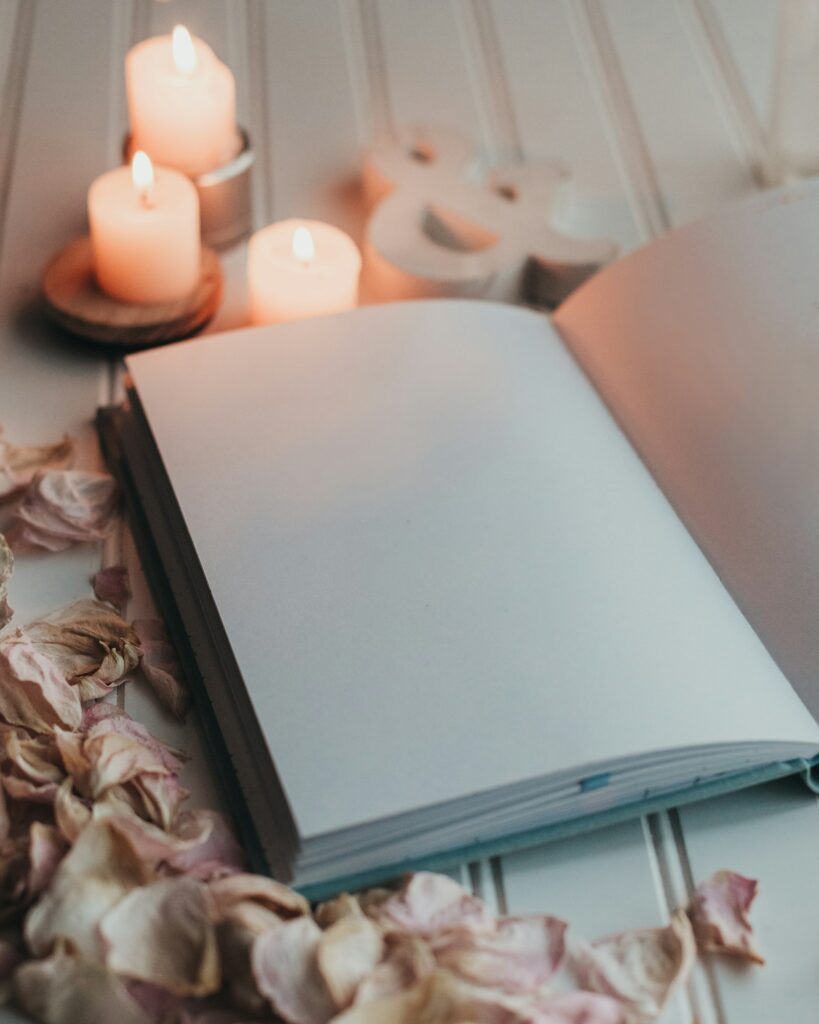 Caderno aberto ao lado de velas acesas