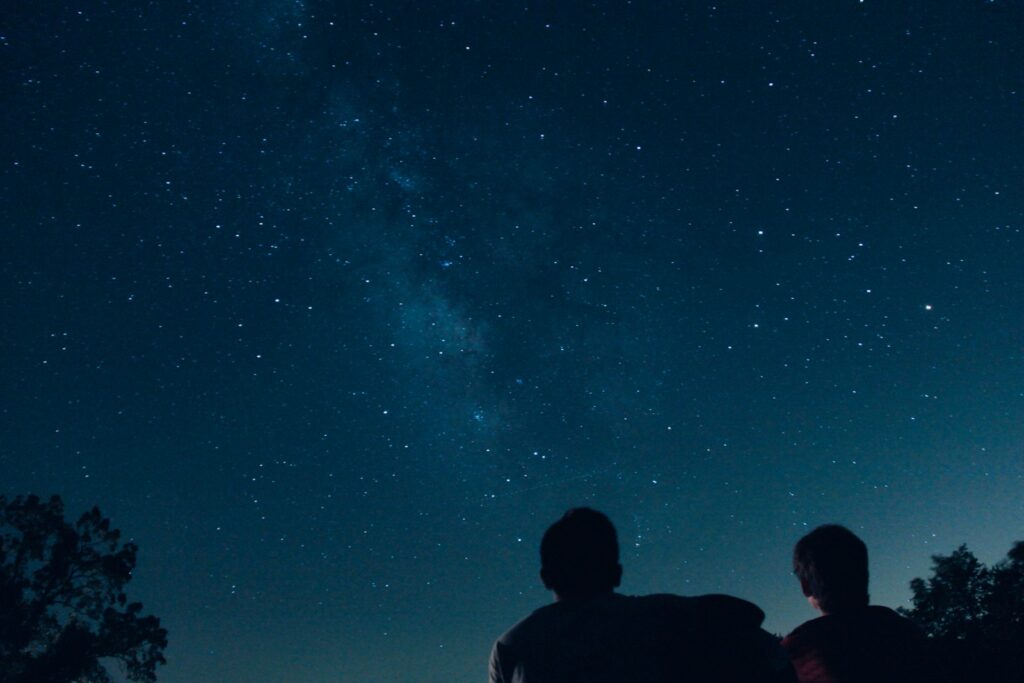 Duas pessoas observando o céu estrelado à noite